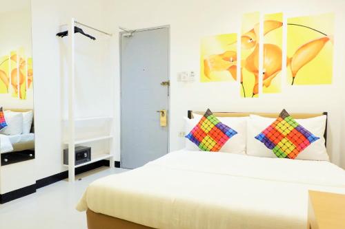 a bedroom with a white bed with colorful pillows at Kamusta Boutique Hotel in Boracay