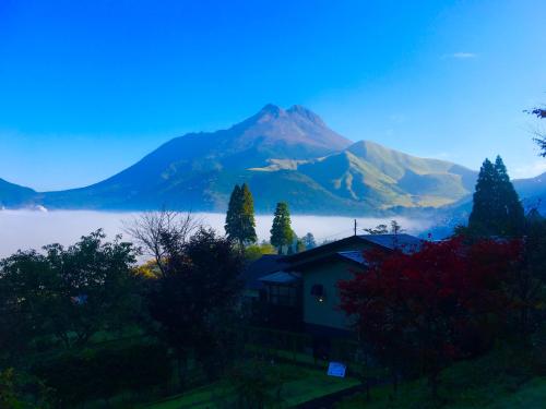 a house with a view of a mountain in the fog at Yufuin-Sanso Waremokou in Yufuin