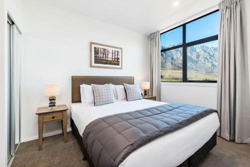 - une chambre avec un grand lit et une grande fenêtre dans l'établissement Kawarau View, à Queenstown