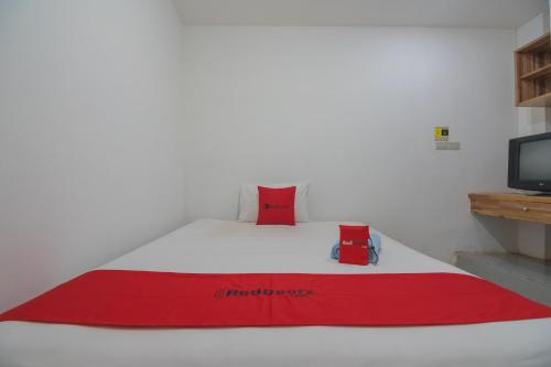a bed with a red blanket on top of it at RedDoorz near Gajah Mada Pontianak in Pontianak