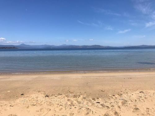a beach with the ocean and mountains in the background at Secret Spot - Bruny Island in Lunawanna