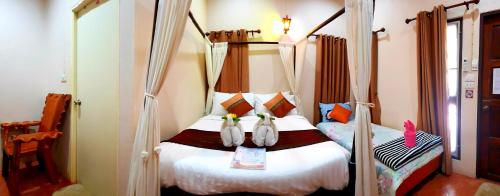 a bedroom with a bed with two penguins on it at Bua Patumma Resort in Mae Sai