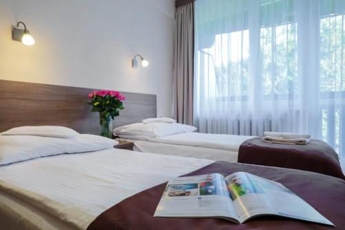 a hotel room with two beds with a book on them at Hotel***NAT Piwniczna Zdrój in Piwniczna-Zdrój