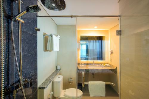 y baño con ducha, aseo y lavamanos. en Swiss-Belhotel Pangkalpinang, en Pangkalpinang