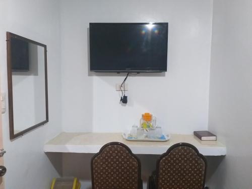 a room with two chairs and a tv on a wall at AMBIANZA APARTELLE in Manila