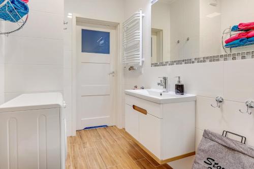 W białej łazience znajduje się umywalka i lustro. w obiekcie Platinium Spectrum Apartment w Gdańsku