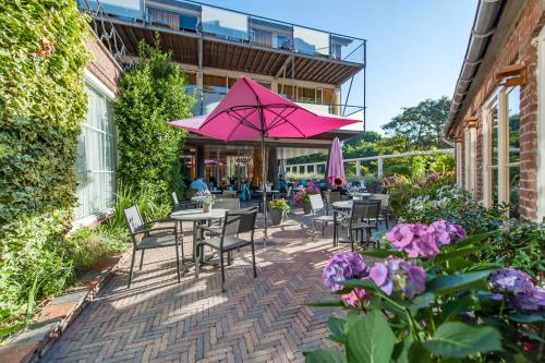 
a patio area with tables, chairs and umbrellas at Duinhotel Zomerlust in Zoutelande
