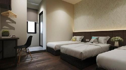 a hotel room with two beds and a desk at The Square Hotel in Skudai