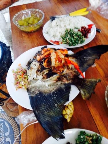 a plate of food with a fish on a table at Pelangi Beach Homestay in Amed