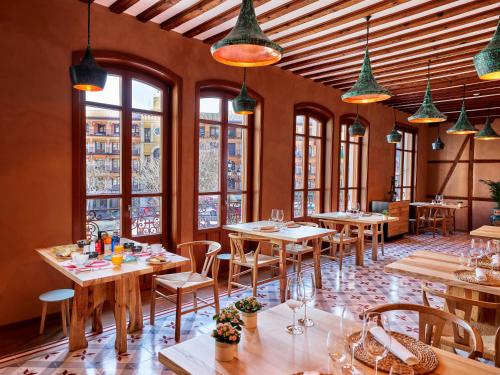 a restaurant with wooden tables and chairs and windows at Hotel Boutique Adolfo in Toledo