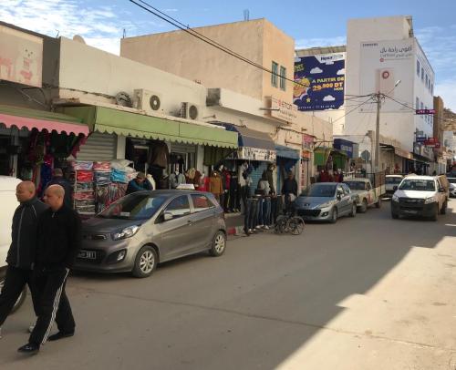 two men walking down a busy city street with cars at Auberge Alferdaous in Tataouine