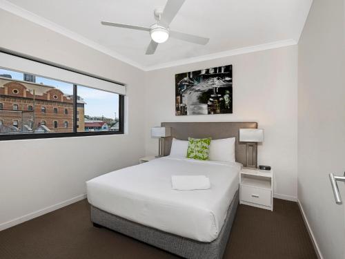 um quarto branco com uma cama e uma janela em Atrio Apartments em Brisbane