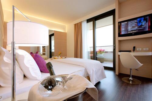 a hotel room with a bed and a television at Laguna Palace Hotel Grado in Grado