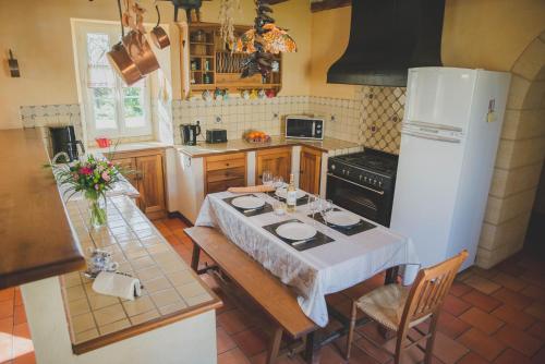 a kitchen with a table and a white refrigerator at La ferme de Bousserand in Pontours