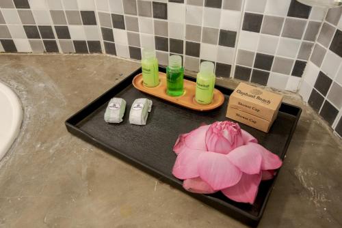 um tabuleiro preto com duas garrafas e uma flor rosa em Hotel Elephant Reach em Yala