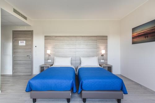 a bedroom with two beds with blue sheets and two tables at Country House Campofiore in Pontelongo
