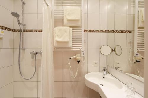 ein weißes Bad mit einer Dusche und einem Waschbecken in der Unterkunft Hotel Karl Noss in Cochem