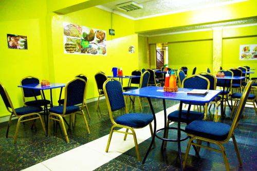 restauracja z niebieskimi stołami i krzesłami oraz żółtymi ścianami w obiekcie Inks Hotel w mieście Nairobi