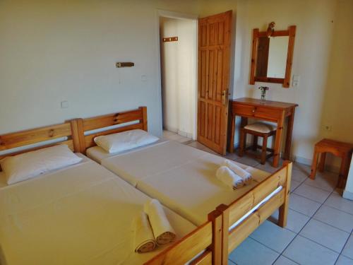 two beds in a room with a sink and a mirror at Lefkothea Apartments in Lefkada