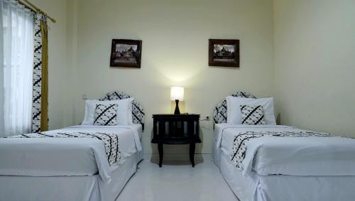 a bedroom with two beds and a lamp on a table at Diana Hotel Jogja in Yogyakarta