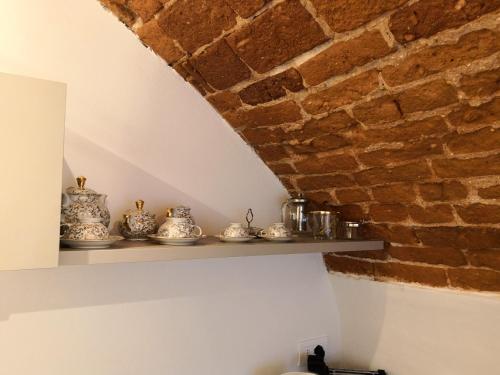a shelf with china on it next to a brick wall at Cupola Rubatti Tornaforte: Apollo e le sue Muse in Cuneo