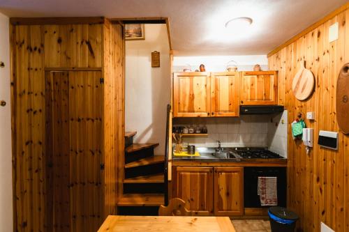 małą kuchnię z drewnianymi szafkami i zlewem w obiekcie Casa Neve w mieście Abetone