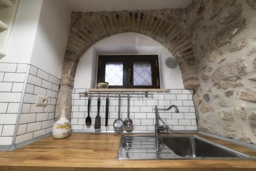 a kitchen with a sink and a brick wall at La Dimora di Ares in Formia