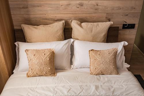 a bed with four pillows and white sheets at Il Bosco apartment in Arco