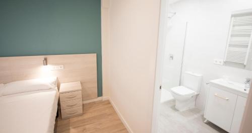 a small bathroom with a bed and a toilet at Happy Hostal Carrales in Burgos