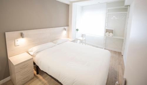a bedroom with a white bed and a window at Happy Hostal Carrales in Burgos