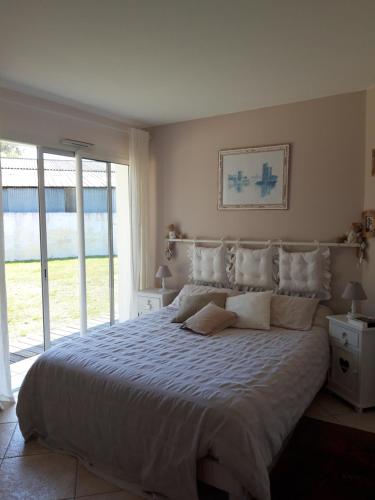 a bedroom with a large bed and a large window at Agréable Maison sur le Bassin d'Arcachon in Andernos-les-Bains