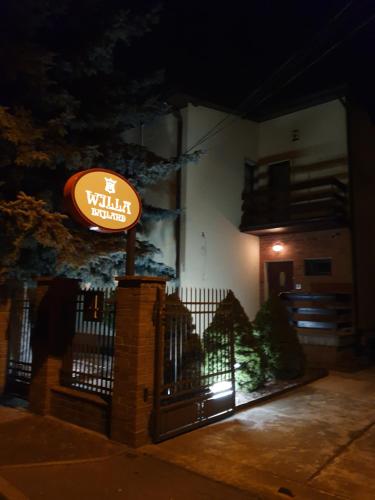 a sign in front of a building at night at WILLA BAJLAND in Warsaw