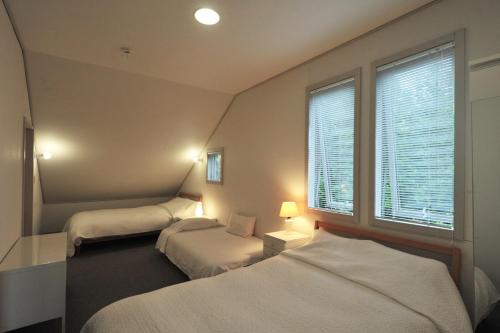 2 camas en una habitación pequeña con ventana en Garden Shed, en Yamanakako