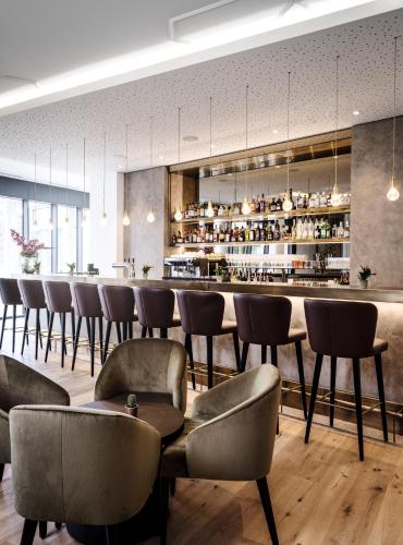 a bar in a restaurant with chairs and a counter at AMERON Neuschwanstein Alpsee Resort & Spa in Schwangau