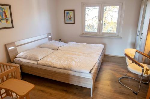 ein Schlafzimmer mit einem Bett, einem Fenster und einem Stuhl in der Unterkunft Ferienwohnung Sonnenseite in Freest