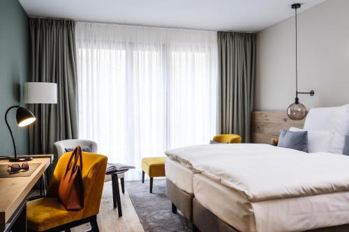 a hotel room with a bed and a desk and chairs at AMERON Neuschwanstein Alpsee Resort & Spa in Schwangau