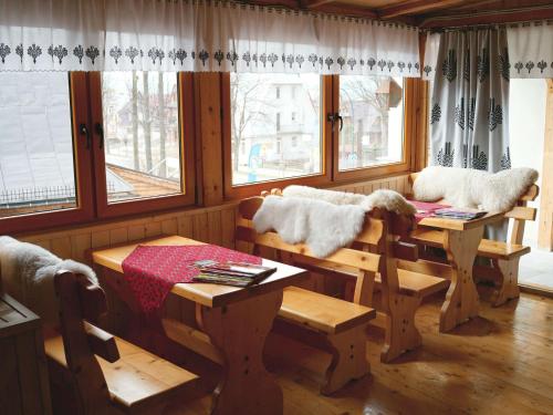 a living room with a table and chairs and windows at Pokoje Zamoyskiego - WATRA in Zakopane