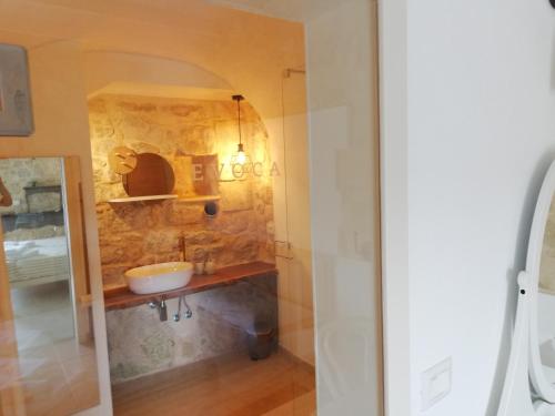 a bathroom with a sink and a stone wall at Evoca in Ragusa