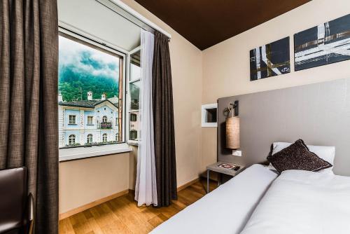 ein Hotelzimmer mit einem Bett und einem großen Fenster in der Unterkunft Hotel Biobistro Semadeni in Poschiavo