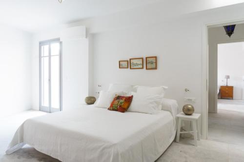 ein weißes Schlafzimmer mit einem großen weißen Bett mit weißer Bettwäsche in der Unterkunft Maison Suisse with sea view in Spetses town in Spetses