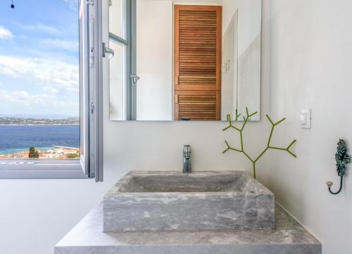 ein Badezimmer mit einem Steinwaschbecken und einem Fenster in der Unterkunft Maison Suisse with sea view in Spetses town in Spetses