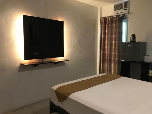 1 dormitorio con 1 cama y TV de pantalla plana en The Blanket Hotel Restaurant & Coffee, en Ilagan