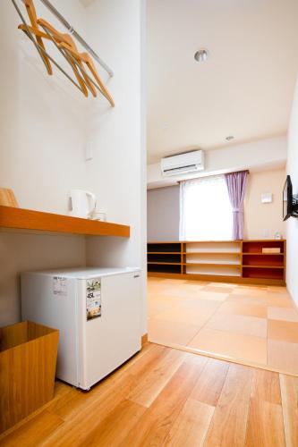 a kitchen with a white refrigerator and a wooden floor at Kansai Seaside Hotel in Kaizuka