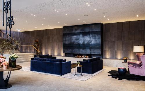 a lobby with two blue couches and a fireplace at AMERON Neuschwanstein Alpsee Resort & Spa in Schwangau