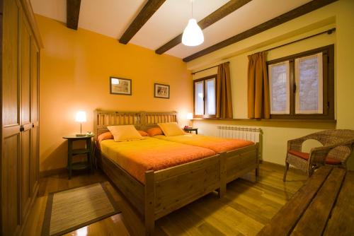 a bedroom with a large bed with orange sheets at Aitonarena Ochagavia in Ochagavía