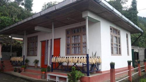 a small white house with baseball bats in front of it at VAMOOSE SALOM NAMCHEBAZAR in Namchi