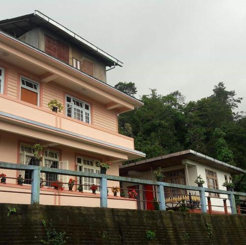 a pink house with a fence in front of it at VAMOOSE SALOM NAMCHEBAZAR in Namchi