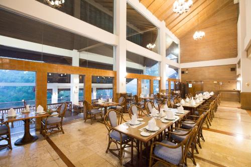 a restaurant with wooden tables and chairs and windows at The Imperial Mae Hong Son Resort in Mae Hong Son
