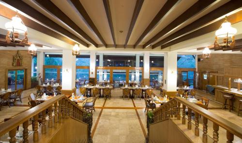 a restaurant with tables and chairs and windows at The Imperial Mae Hong Son Resort in Mae Hong Son