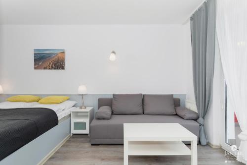 コウォブジェクにあるJantar Apartamenty - Promenada Kołobrzegの小さなベッドルーム(ベッド1台、ソファ付)
